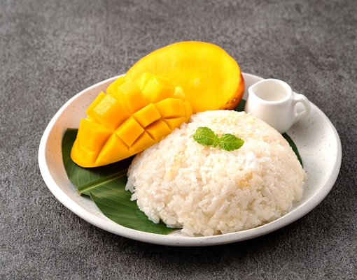 Mango sticky rice dessert on a plate with coconut sauce, Thailand.
