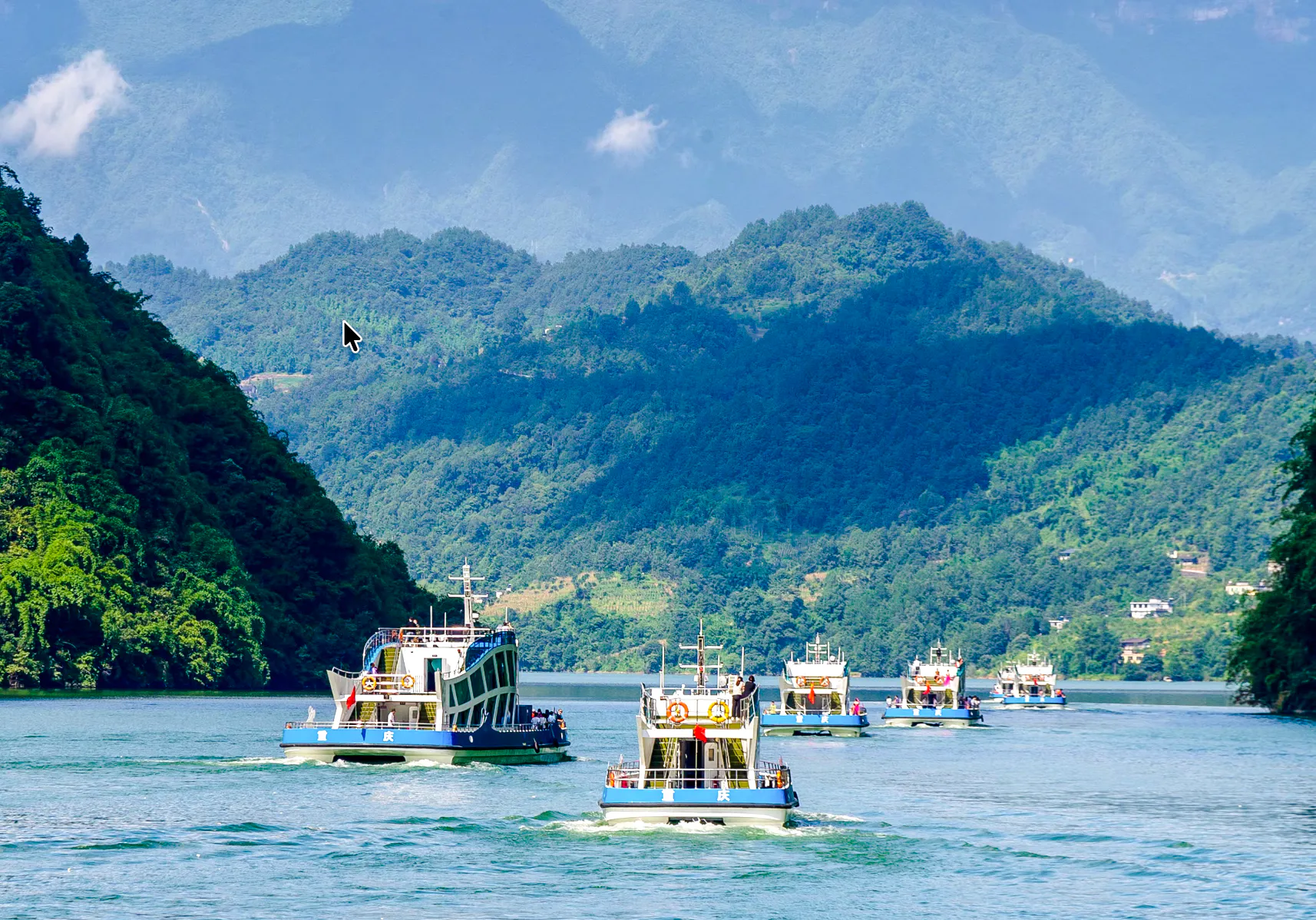 Boats cruising on Furong River with lush green mountains in Chongqing.