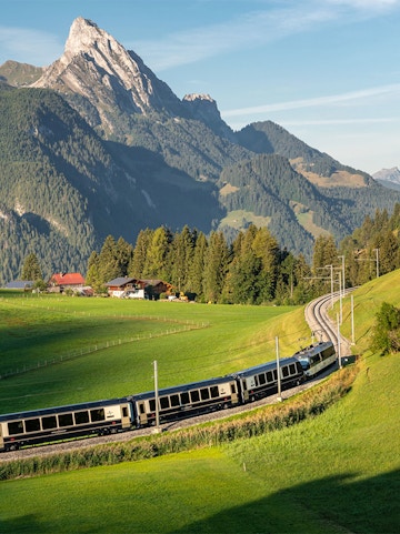 Train on Golden Pass route through Swiss Alps with mountain backdrop.