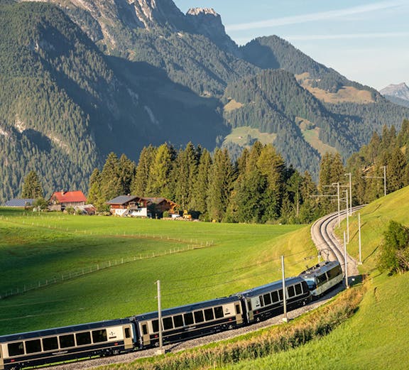 Train on Golden Pass route through Swiss Alps with mountain backdrop.