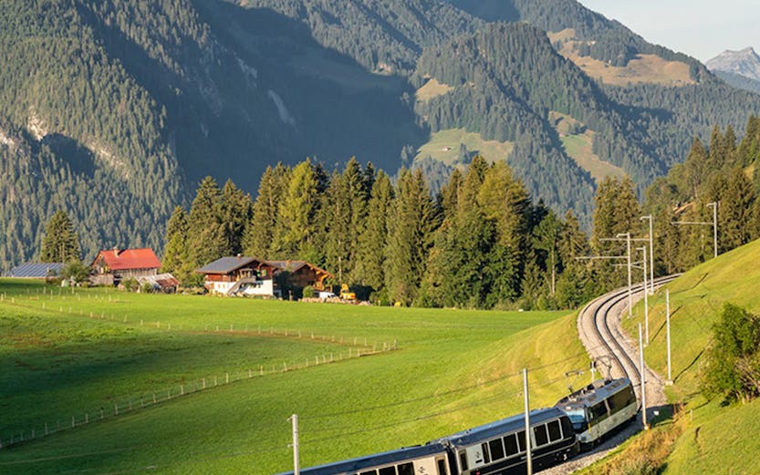 Train on Golden Pass route through Swiss Alps with mountain backdrop.