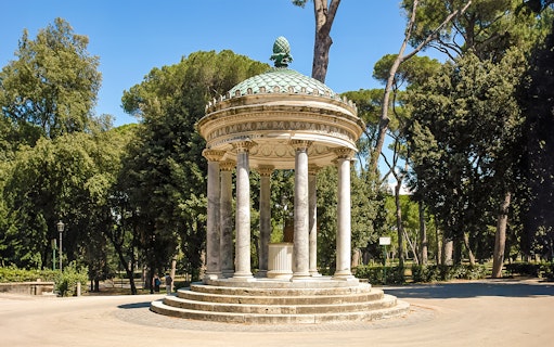Temple of Diana in Villa Borghese, Rome, surrounded by trees and clear sky.