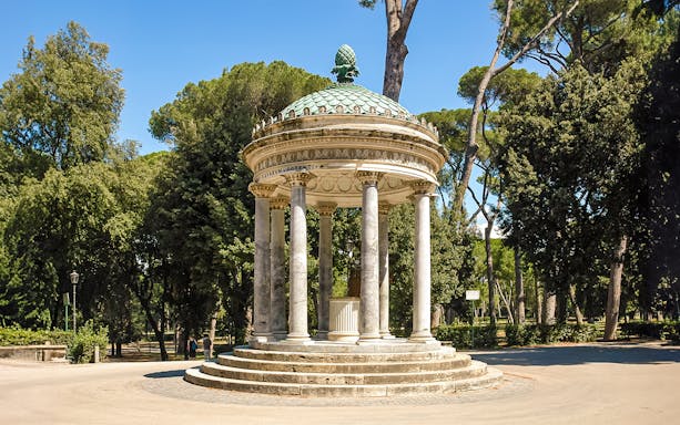 Temple of Diana in Villa Borghese, Rome, surrounded by trees and clear sky.