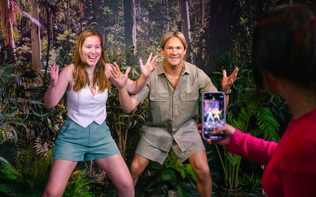 Guest posing with Steve Irwin figure in a jungle-themed setting.