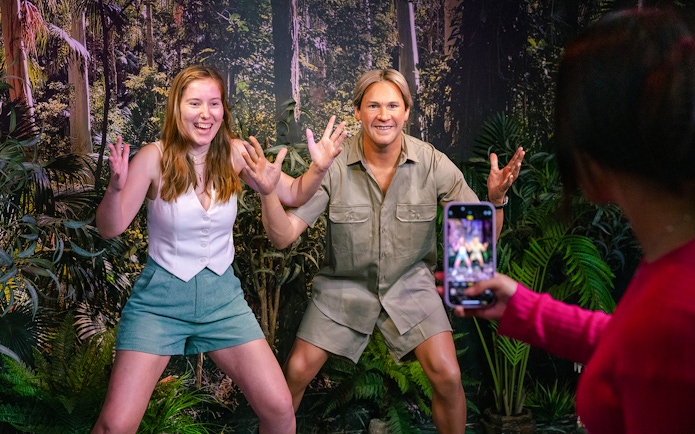 Guest posing with Steve Irwin figure in a jungle-themed setting.