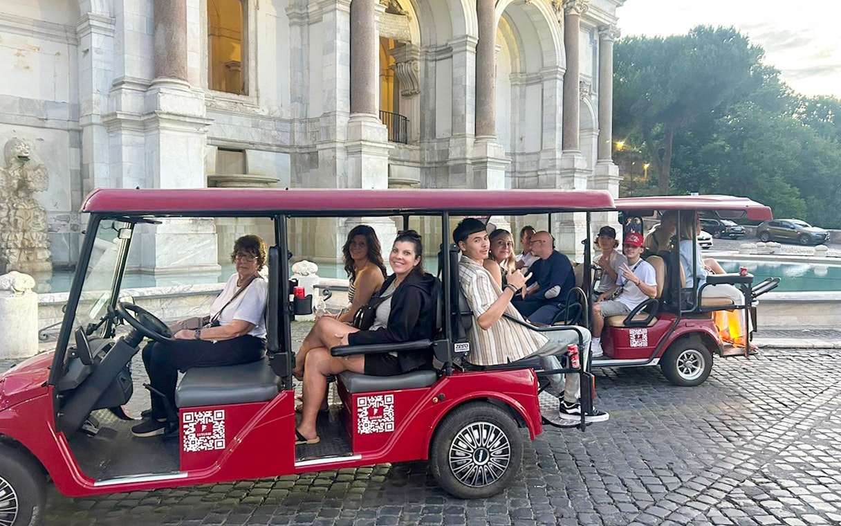 Tourists on a golf cart tour in front of a historic building in Rome.