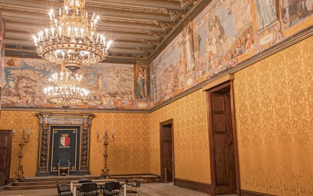 Grand hall with ornate chandeliers and historical frescoes in Malta's heritage site.