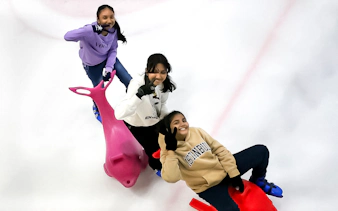 Three people ice skating with dolphin-shaped aids at Blue Ice Snow Park, Pavilion Bukit Jalil.