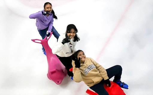 Three people ice skating with dolphin-shaped aids at Blue Ice Snow Park, Pavilion Bukit Jalil.