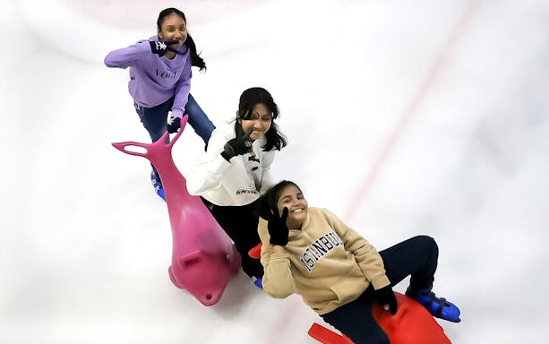 Three people ice skating with dolphin-shaped aids at Blue Ice Snow Park, Pavilion Bukit Jalil.