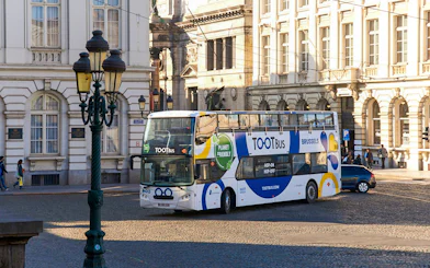 Hop on hop off bus in Brussels city center near historic buildings.