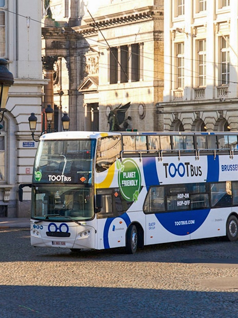 Hop on hop off bus in Brussels city center near historic buildings.