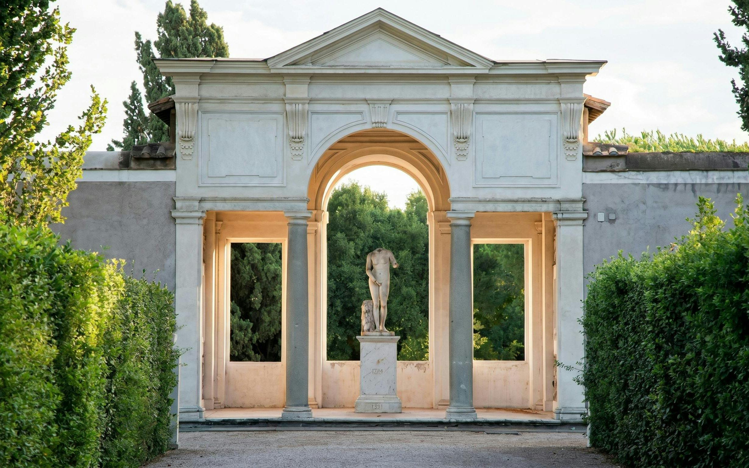 Statue in archway at Villa Medici, Rome, surrounded by greenery.