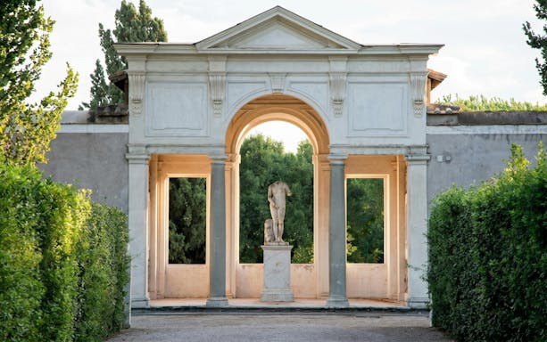 Statue in archway at Villa Medici, Rome, surrounded by greenery.