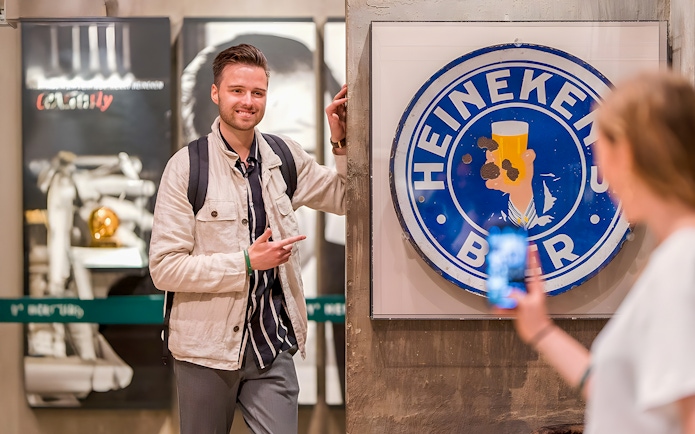 Guests enjoying the Heineken Experience in Amsterdam with a vintage sign.