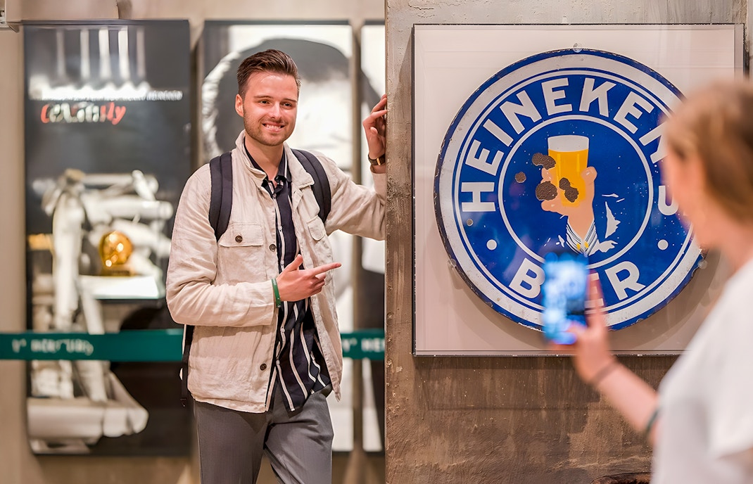 Guests enjoying the Heineken Experience in Amsterdam with a vintage sign.
