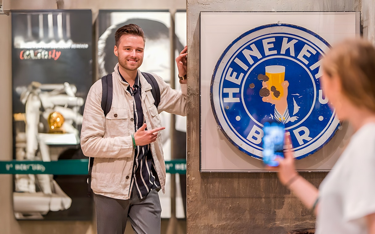 Guests enjoying the Heineken Experience in Amsterdam with a vintage sign.