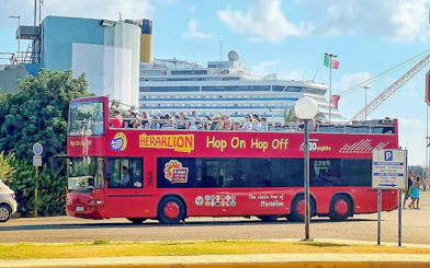 Heraklion Hop-On Hop-Off bus with tourists near a cruise ship.