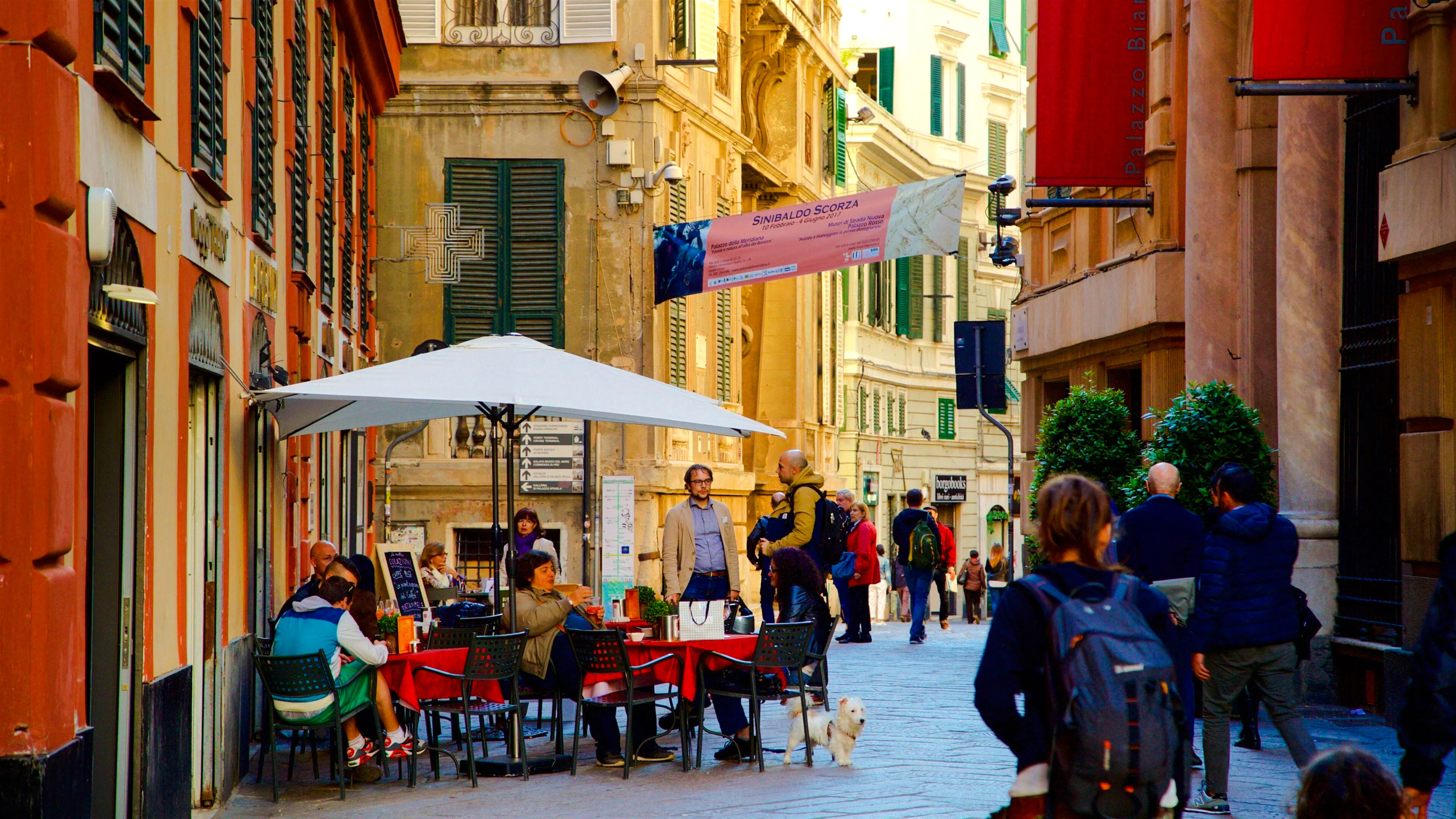 Walking dinner tour in Genoa with people dining at an outdoor café on a narrow street.