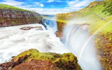 Gullfoss waterfall cascading over rocky cliffs in Iceland with a rainbow.