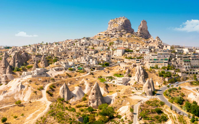 Uchisar Castle atop rock formations in Cappadocia, Turkey, with surrounding village.