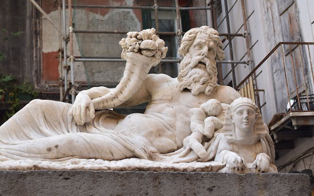 Marble statue in Quartieri Spagnoli, Naples, depicting a reclining figure with a cornucopia.