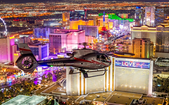 Helicopter flying over illuminated Las Vegas Strip during 60-min Red Rock Canyon tour.