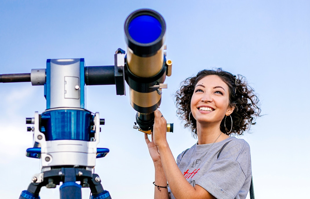Girl observing the Eiffel Tower through a telescope in Paris, France.