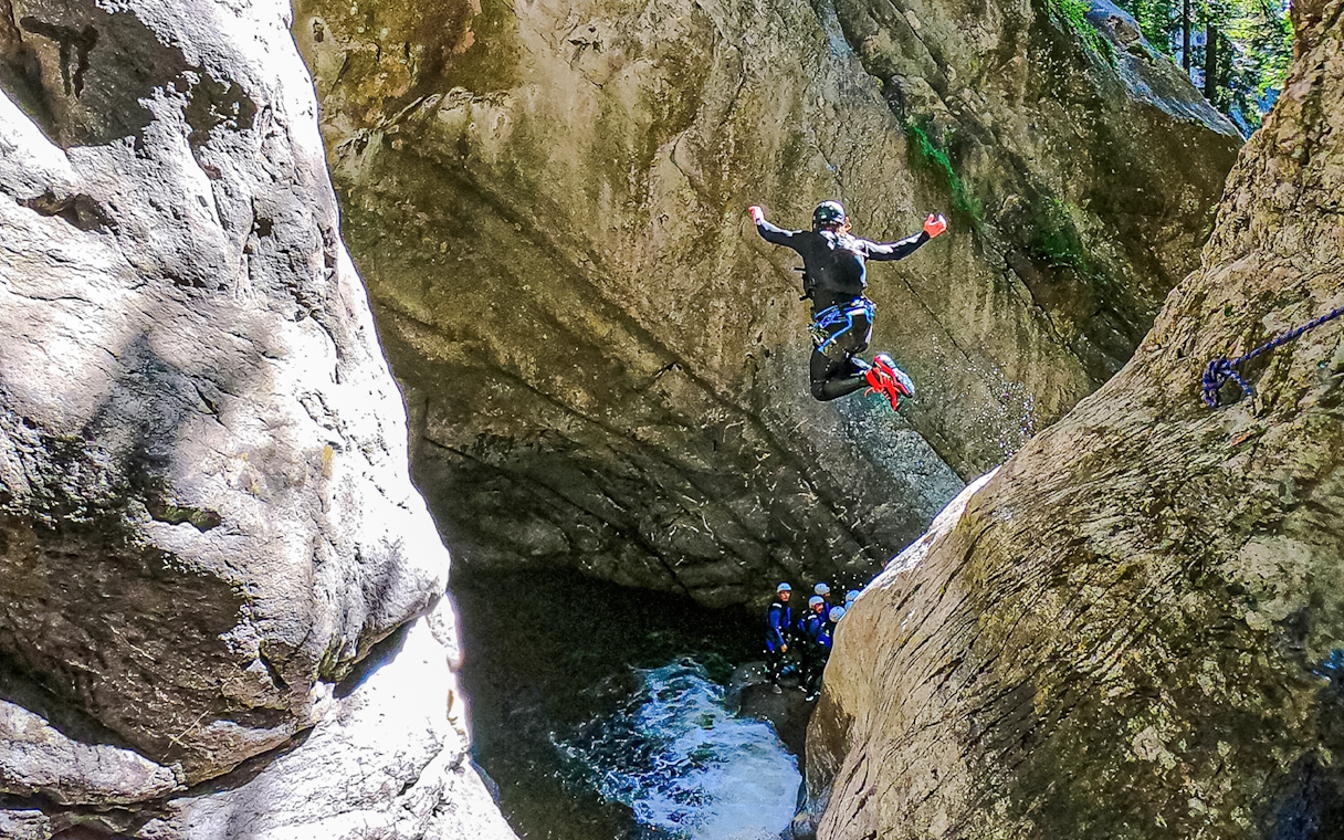 Person jumping into a canyon pool during canyoning in Interlaken.