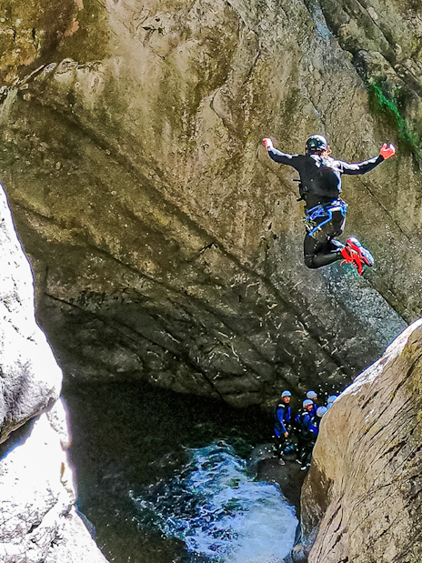 Person jumping into a canyon pool during canyoning in Interlaken.