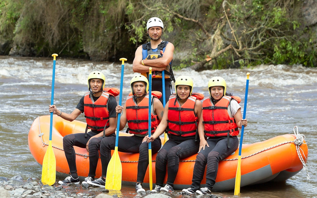 Group preparing for guided rafting on Tully River in an orange raft.