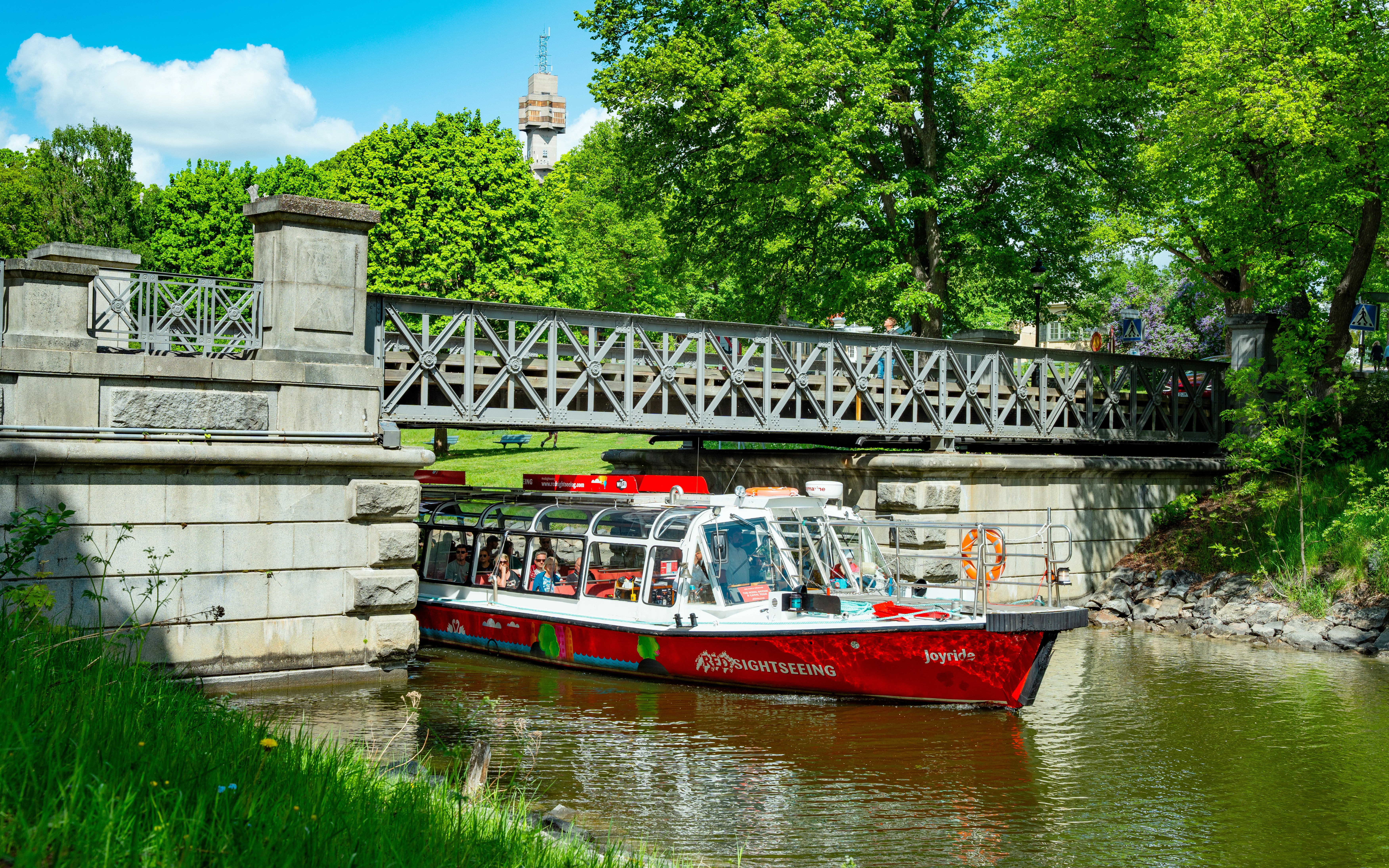 Sightseeing boat on Djurgårdsbrunn Canal, Djurgården, passing under a bridge.