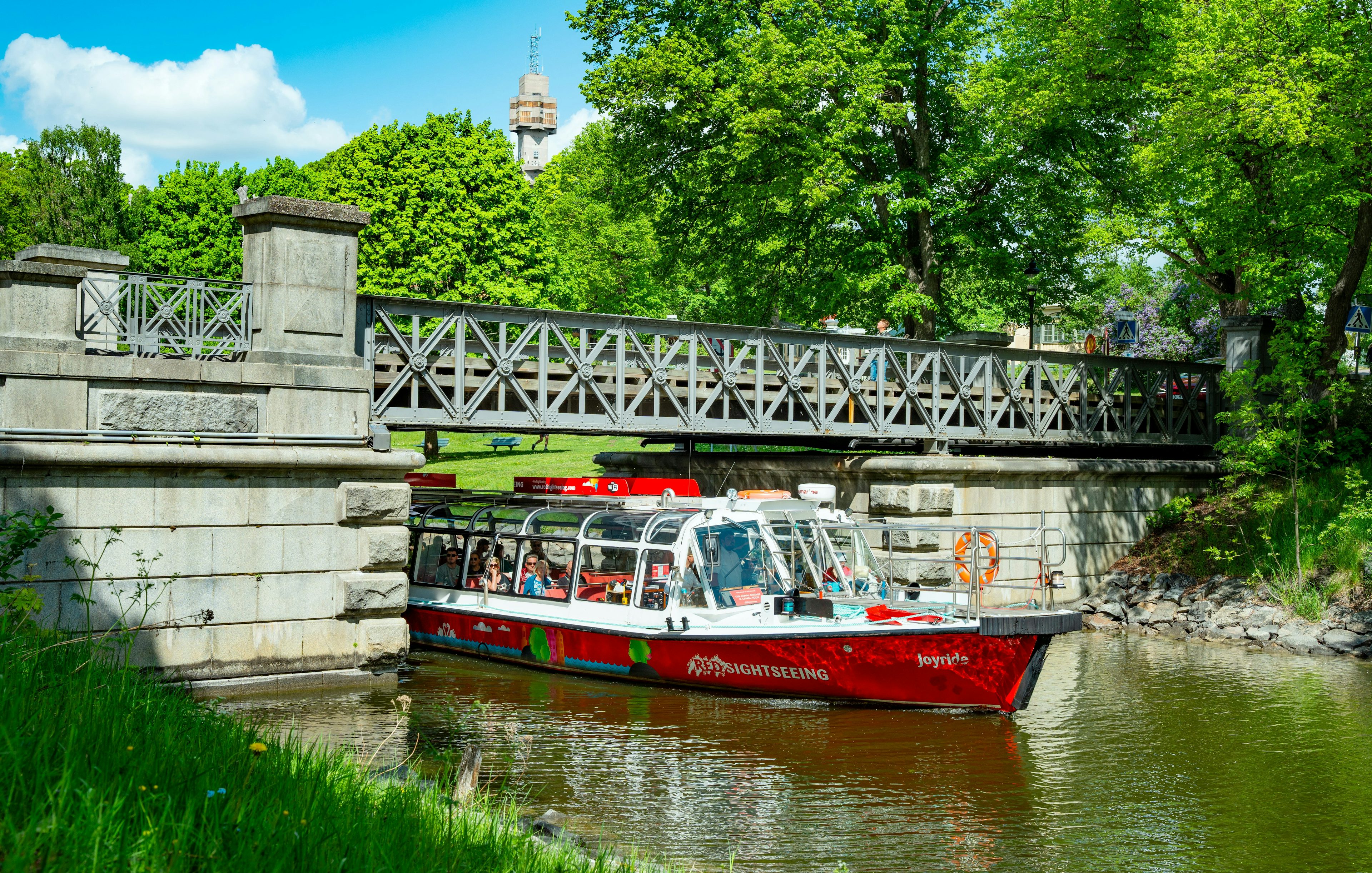 Sightseeing boat on Djurgårdsbrunn Canal, Djurgården, passing under a bridge.