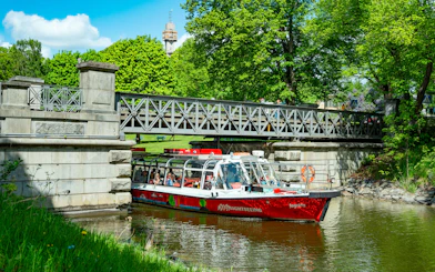 Sightseeing boat on Djurgårdsbrunn Canal, Djurgården, passing under a bridge.