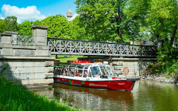 Sightseeing boat on Djurgårdsbrunn Canal, Djurgården, passing under a bridge.