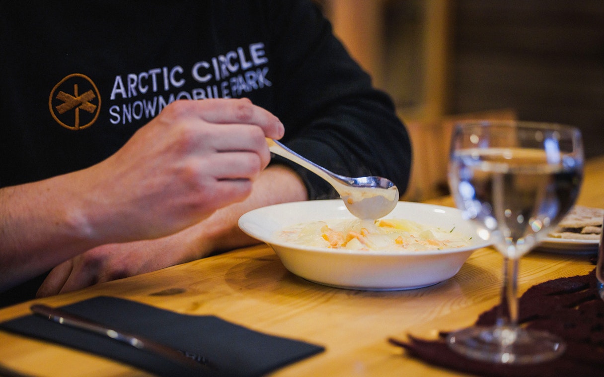 Person enjoying salmon soup in Lapland restaurant.