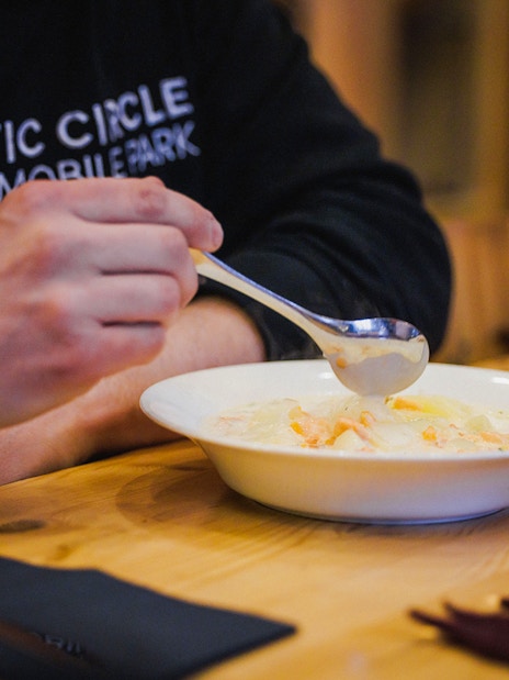 Person enjoying salmon soup in Lapland restaurant.