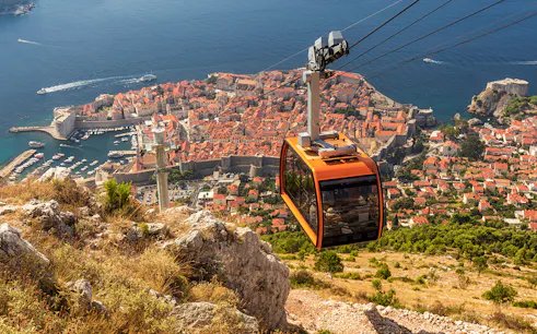 Cable car ascending over Dubrovnik with view of Old Town and Adriatic Sea.