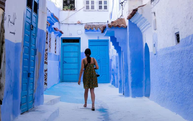 Woman walking through blue alley in Chefchaouen, Morocco.