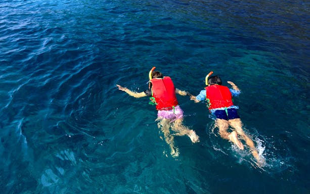 Two people snorkeling in clear blue water during Athens cruise.