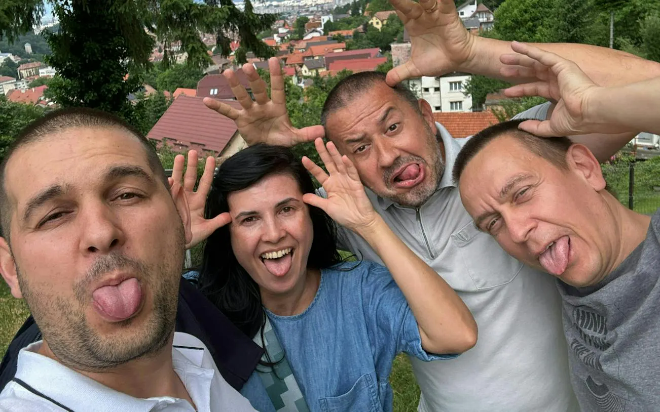 Group of people making funny faces with Brașov cityscape in the background.