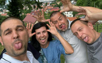 Group of people making funny faces with Brașov cityscape in the background.