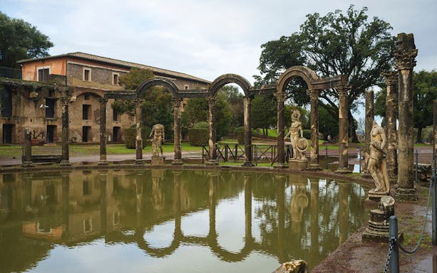Tivoli's Villa Adriana reflecting pool with ancient statues and arches.