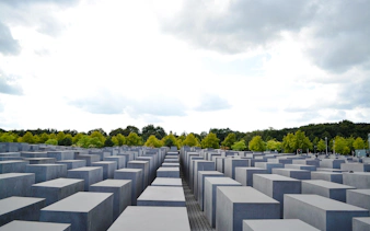 Holocaust Memorial in Berlin with concrete slabs and trees in the background.