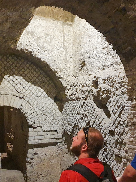 Tourists exploring ancient underground ruins in Naples, Italy during a guided city tour.