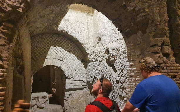 Tourists exploring ancient underground ruins in Naples, Italy during a guided city tour.