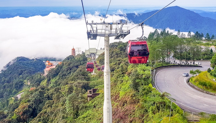Genting Highlands cable cars over lush mountains with a pagoda in the distance.