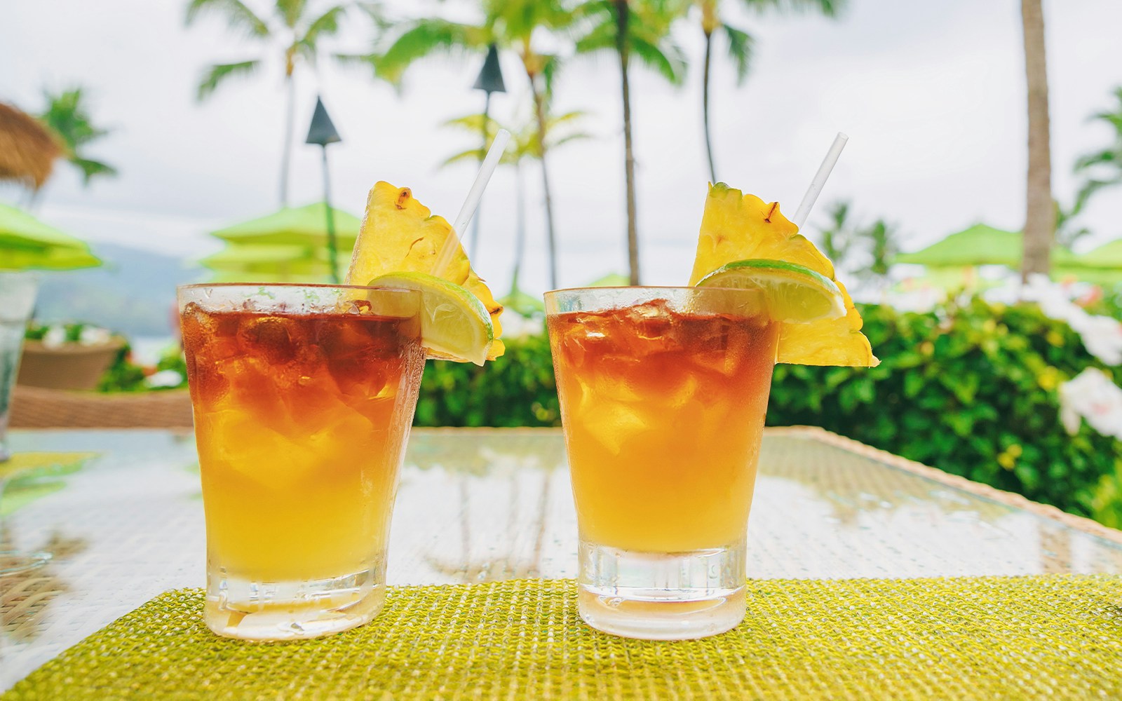 Mai tai cocktails with pineapple garnish in a tropical Hawaiian setting.
