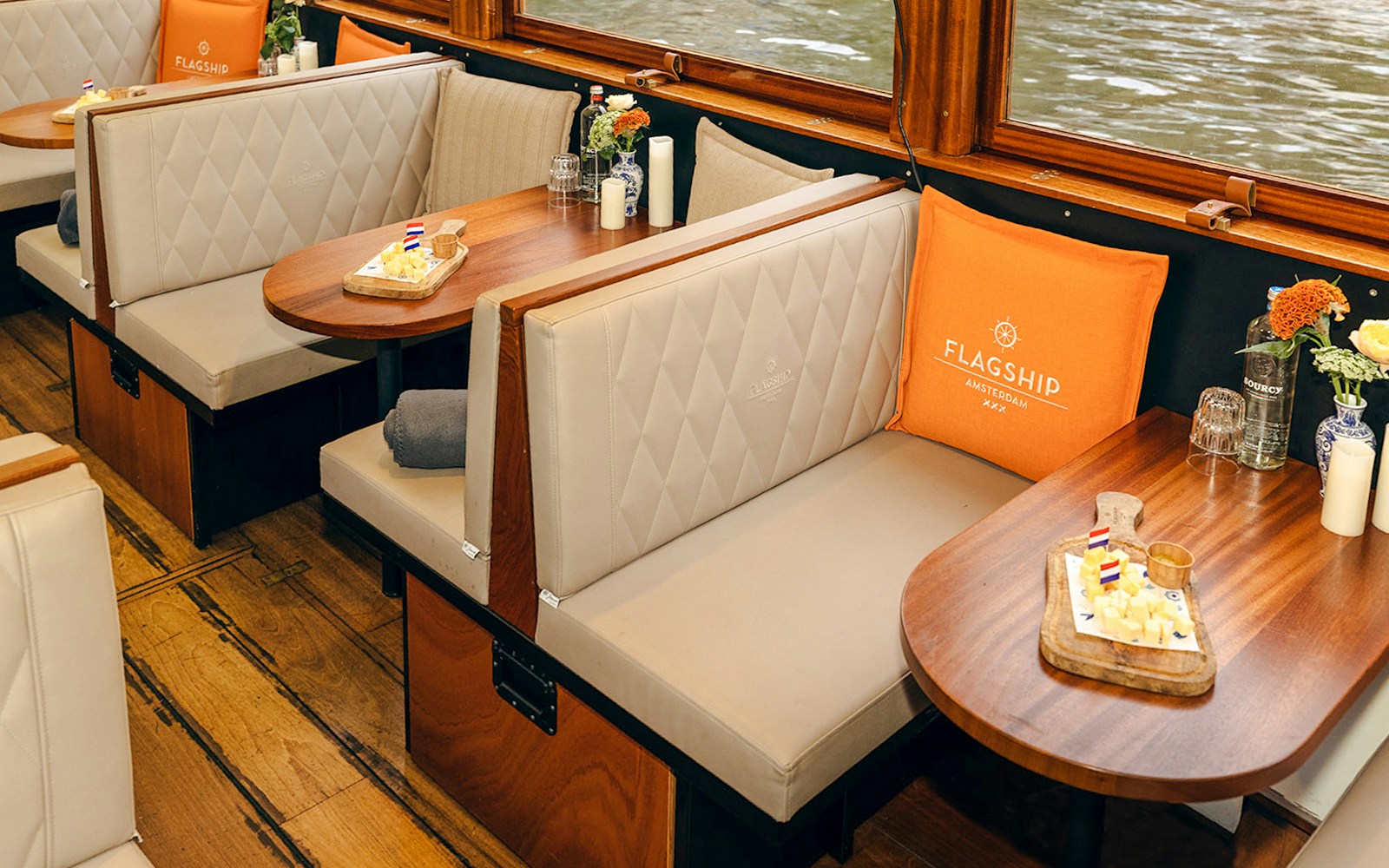 Cozy seating with snacks on a wooden table inside a canal boat in Amsterdam.