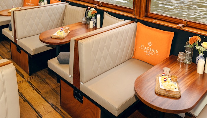 Cozy seating with snacks on a wooden table inside a canal boat in Amsterdam.